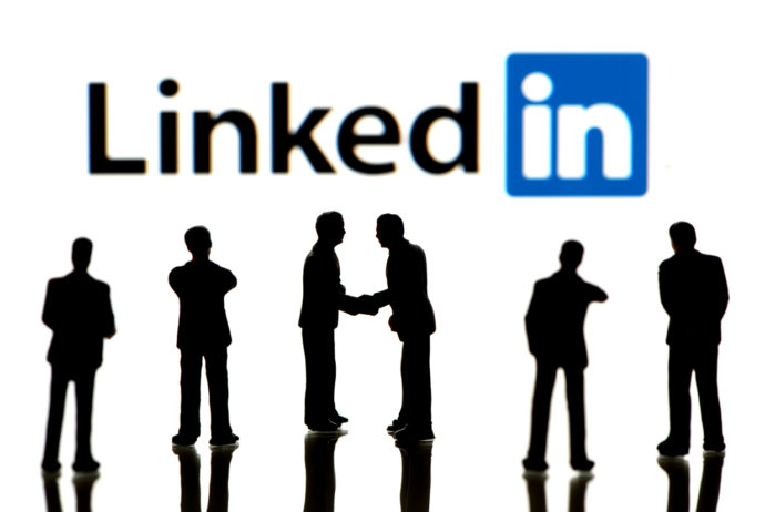 Business figurines standing in front of Apple iPad monitor displaying LinkedIn logo. LinkedIn is a social networking service for people in professional occupations. Ways to Generate Sales Leads With LinkedIn concept